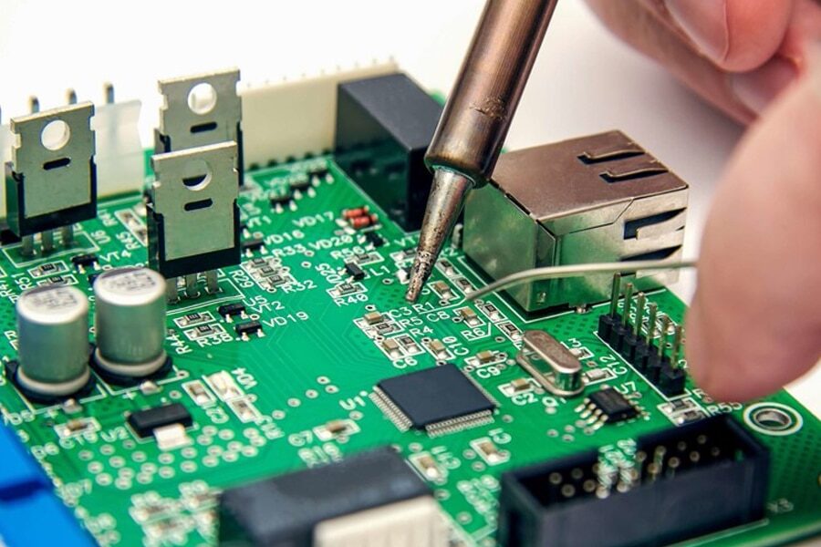 Engineer inspecting assembled PCB under stereo microscope