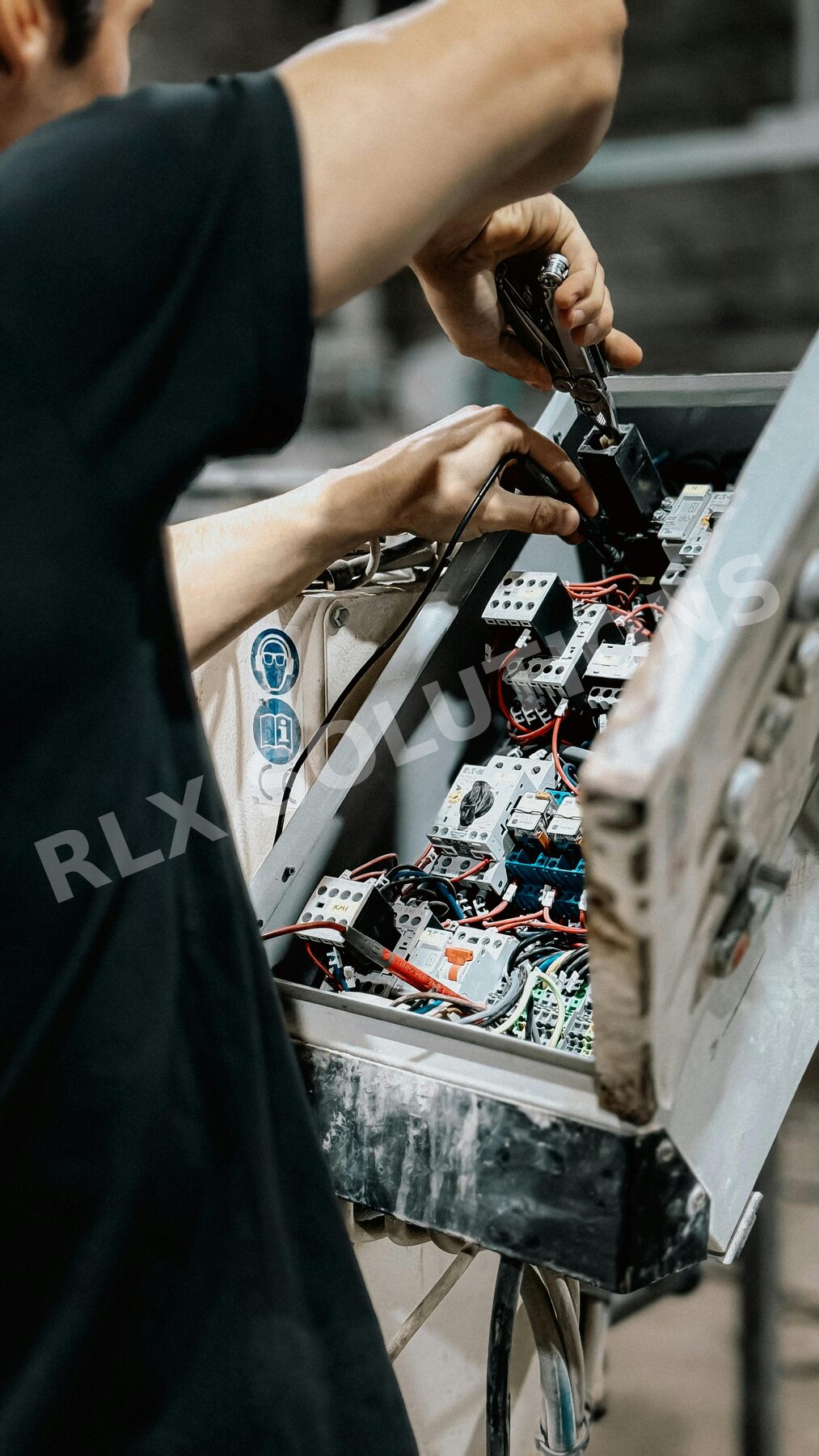 Technician wiring an industrial control panel with terminal blocks and contactors